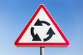 Close-up of roundabout road sign on background of blue sky. Royalty Free Stock Photo