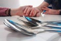 Close up of row of spoons on table, with hands held in background