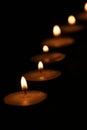 Close-up of a row of tealight candles burning in a dark room Royalty Free Stock Photo