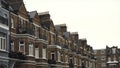 Close-up of Row of typical English terraced brick houses against the grey sky in autumn day. Action. Traditional English