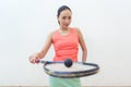 Close-up of a rubber hollow ball on the new squash racket of a fit woman