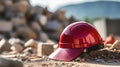 Close up of a ruby Working Helmet on Gravel. Blurred Construction Site Background