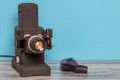 Close-up of a running old black projector for viewing slides and filmstripes and a negative film on table over blue background. Royalty Free Stock Photo