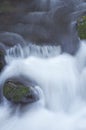 Close up of rushing river water flowing over mossy rocks