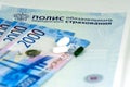 Close-up of Russian health insurance policy, Russian cash banknotes and a few pills. Rissians rubles