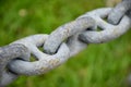 Close up rusted gray iron chain or steel rings connected together on grass green background Royalty Free Stock Photo