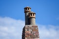 Close up of a rustic brick chimney with two decorative clay chimney pots under a bright blue sky Royalty Free Stock Photo