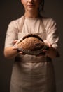 Close up of rustic sourdough bread held by female baker, highlighting handmade crust texture and traditional bakery process Royalty Free Stock Photo