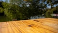 Close-up of a rustic wooden tabletop with a vibrant natural backdrop of greenery and water Royalty Free Stock Photo