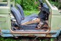 Close-up of a rusty, abandoned car standing in the yard among the green grass in the open air. The car is disassembled for spare p