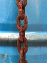 Close-up of a rusty chain in front of blue rusty steel drum Royalty Free Stock Photo