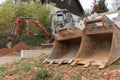 Close-up of rusty excavator buckets lying on the ground at a construction site. A mini digger and private house are visible in the Royalty Free Stock Photo