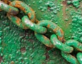 Close-up of a rusty and weathered metal chain with green paint, highlighting texture contrast