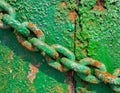 Close-up of a rusty and weathered metal chain with green paint, highlighting texture contrast