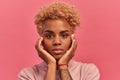 Close up of sad african american woman with hands near face on pink background. Royalty Free Stock Photo