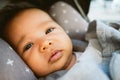 Close up of sad cute baby girl laying in a pram or stroller with dark eyes. baby with upset face alone in stroller Royalty Free Stock Photo