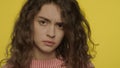 Close up of sad girl face. Offended woman looking to camera on yellow background