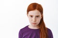 Close up of sad redhead girl with freckles sulking, angry or gloomy looking at camera, being upset or jealous, frowning Royalty Free Stock Photo