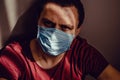 Close up sad thoughtful adult man portrait in medical mask sit leaning on wall with stare eyes. Stay isolation at home. Quarantine Royalty Free Stock Photo