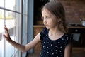 Close up sad upset little girl looking out window