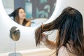 Close up of sad young Asian woman using wooden comb brush her damaged and tangled wet hair in front of mirror Royalty Free Stock Photo