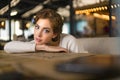 Close up of sad young woman deep in thought outdoors. Portrait of young cute elegant woman sitting outdoor in a cafe in