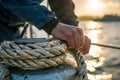 Close-up of a sailor& x27;s hands tying a knot on the ship at sunset