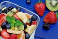 Salad with fresh fruits and berries in a bowl on blue wooden table Royalty Free Stock Photo
