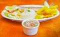 Close up of sald inside of a white bowl and a blurred fried fish served in a white plate over a wooden table Royalty Free Stock Photo