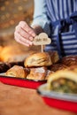 Sales Assistant In Bakery Putting Dairy Free Label Into Stack Of Freshly Baked Baked Cinnamon Buns Royalty Free Stock Photo