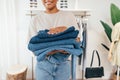 Close-up of saleswoman carrying clothing in a small retail store. Cropped shot of female holding a pile of jeans Royalty Free Stock Photo