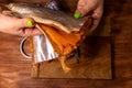 Close-up of salmon carcass with fillet on the background of a cutting board, female hands hold it