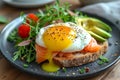 A close-up salmon and cooked egg sandwich garnished with greens, spotlighting the textures and colors. It reflects a