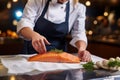 Close up salmon fillet and hand of chef woman in uniform.