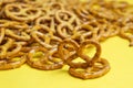 Close-up of salted mini pretzels on a yellow background. Popular beer snack