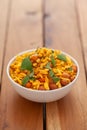 Close up of salted peanut mixed Indian namkeen snacks with green curry leaves  in in white ceramic bowl over wooden  background Royalty Free Stock Photo