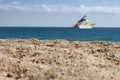 Close-up of the sand on a beach with a yacht out of focus in the background on a summer day.