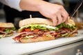 a close-up of a sandwich artist putting last touches on a crispy bacon sandwich