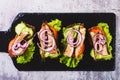 Close up of sandwiches on rye bread with tomatoes, cucumber, sprats and onions on slate top view Royalty Free Stock Photo