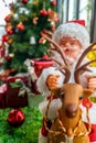 Close up of santa claus doll riding on reindeer with blurred decoration christmas tree Royalty Free Stock Photo