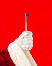 Close-up of Santa Claus`s hand holding a toothbrush up.Concept of  healthy lifestyle, daily hygiene. Red background with copy Royalty Free Stock Photo