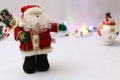 Close up of a Santa Puppet with snowmen in the background with some Festive Christmas Lights