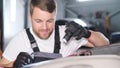 Close-up of satisfied attractive auto mechanic inspecting car with flashlight