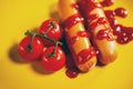 Close up of sausages in sauce with cherry tomatoes. Appetizing frankfurters with small red tomatoes and ketchup on