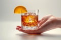 Close-up of a Sazerac cocktail in hand with a white backdrop