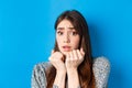 Close-up of scared timid girl looking afraid, shaking from fear, press hands to body and staring frightened, standing on