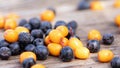 Close-up of scattered fresh sea buckthorn berries and chokeberry on wooden table. Garden gifts. Handful of berries gathered. Royalty Free Stock Photo