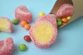 Close up scattering multicolored candies, jelly and sweets with cone on blue background.