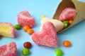 Close up scattering multicolored candies, jelly and sweets with cone on blue background.