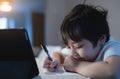 Close up Schoolboy using black pen drawing on white paper sheet, Young kid using tablet for school homework online on internet, Royalty Free Stock Photo